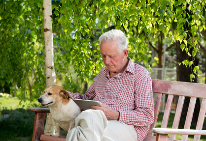 Senior Relaxing on Bench with Dog & Tablet